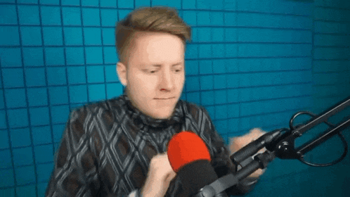 a man is standing in front of a microphone in a studio .