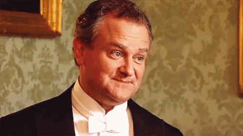 a man in a tuxedo and bow tie is making a silly face .