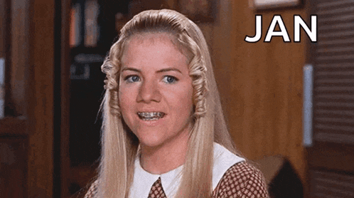 a woman with braces on her teeth is making a funny face in front of a sign that says jan .