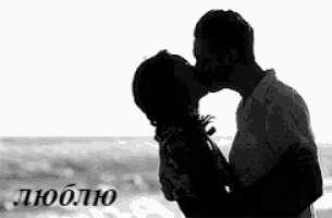 a black and white photo of a man and a woman kissing on the beach