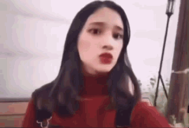 a woman in a red sweater is making a funny face while sitting on a bench .