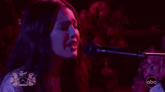a woman is playing a piano in front of a crowd .