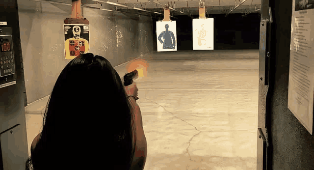 a woman is shooting a gun at a target that says 100 on it