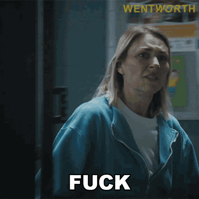 a woman in a blue jacket says " fuck " in front of a wall