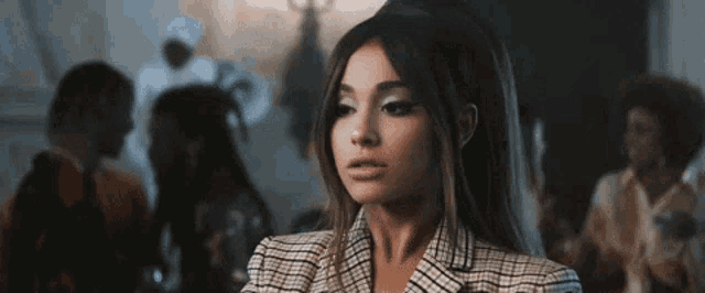 ariana grande is wearing a plaid jacket and standing in front of a group of women .