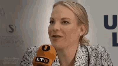 a woman is talking into a microphone while wearing a floral jacket .