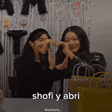 two girls are making a heart shape with their hands and the words shofi y abri are written below them