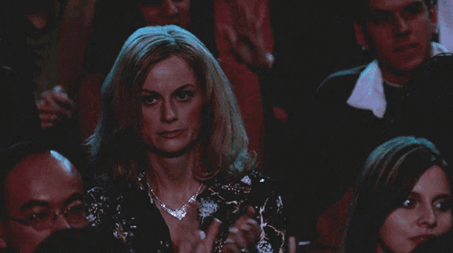 a woman sitting in a crowd holds a ring in her hand