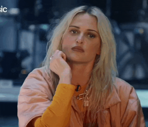 a woman with blonde hair is wearing a yellow shirt and a pink jacket .