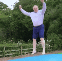 a man in a white shirt and blue shorts is jumping on a blue inflatable trampoline .