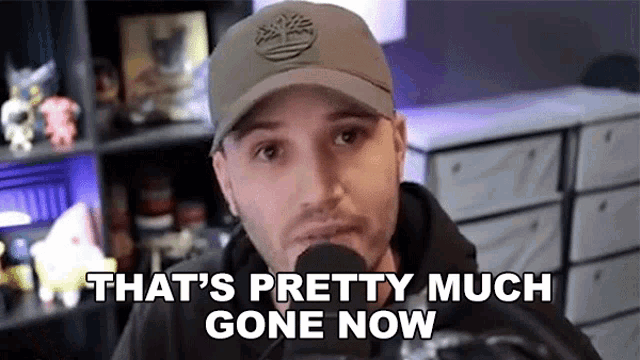 a man wearing a hat is talking into a microphone and saying that 's pretty much gone now .