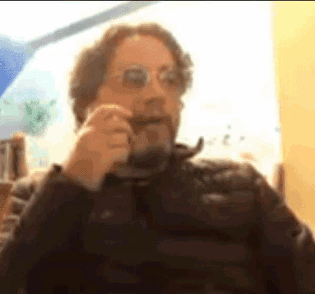 a man with a beard and glasses is drinking from a mug .
