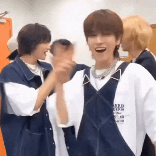 a group of young men are standing next to each other in a room and laughing .