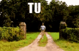a man is running down a dirt road in front of a sign that says " tu "