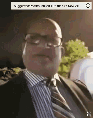 a man wearing glasses and a suit is standing in front of a screen that says suggested