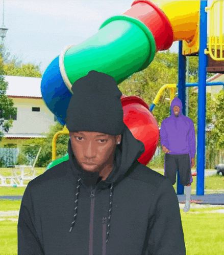 a man in a black hoodie stands in front of a colorful slide