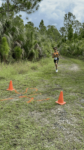 a person running on a dirt path with cones on the side