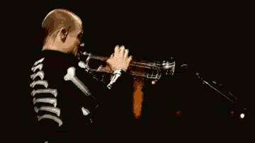 a man in a skeleton costume plays a trumpet in front of a microphone