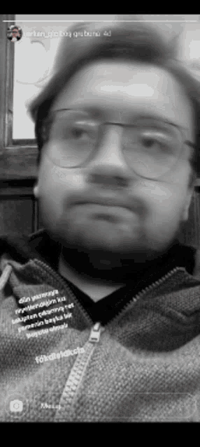 a black and white photo of a man wearing glasses and a zipper jacket