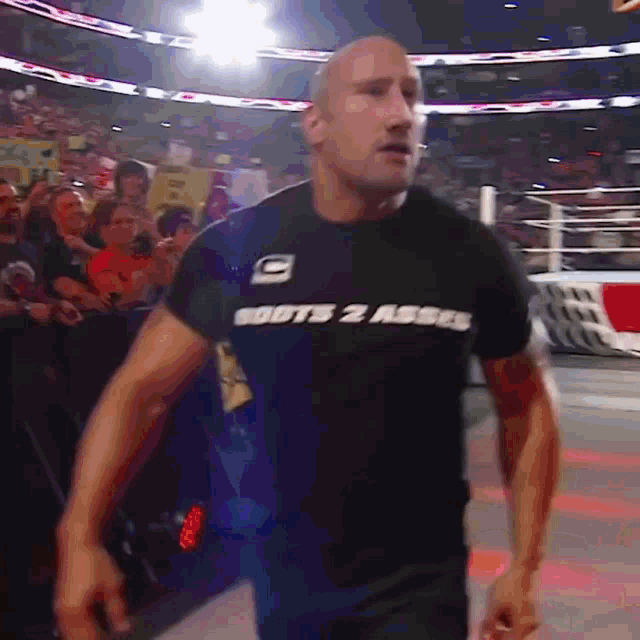 a man wearing a boots 2 asses t-shirt walks into a wrestling ring