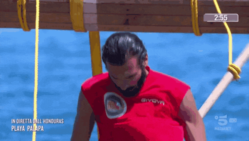 a man in a red givova shirt is standing in the water