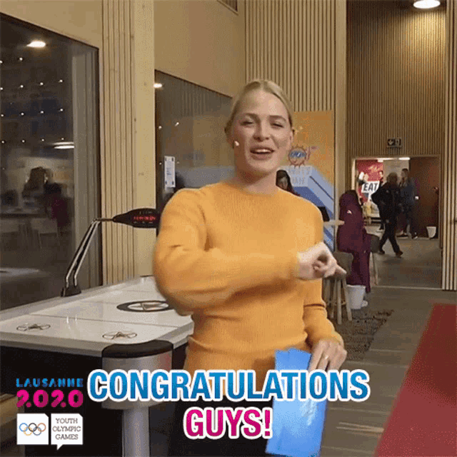a woman in a yellow sweater says congratulations guys in a video