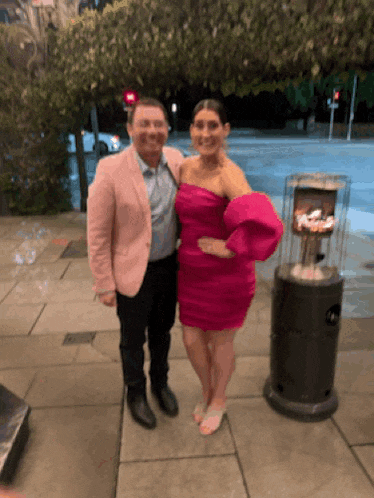 a man in a pink jacket and a woman in a pink dress are posing for a picture