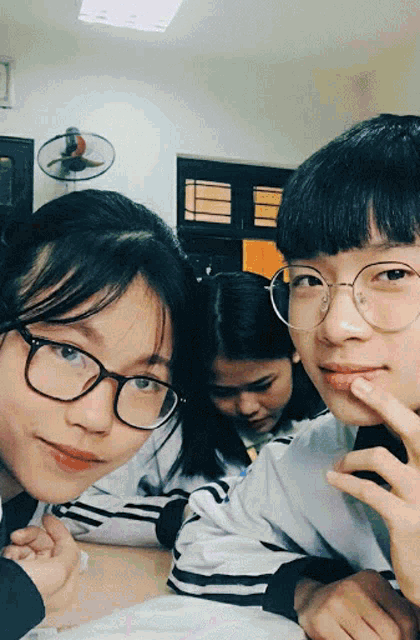 a girl wearing glasses is sitting next to a boy