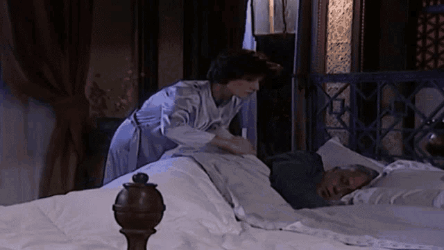 a woman is putting a blanket on an older man 's head