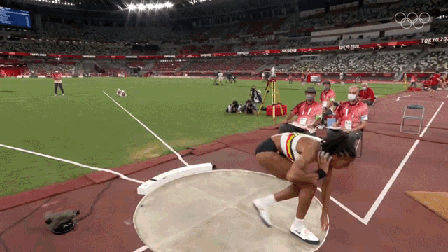 a female athlete prepares to throw a discus in front of a crowd at the tokyo olympics