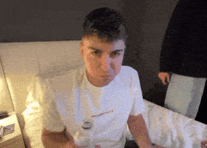 a man in a white shirt is sitting on a bed with his mouth open