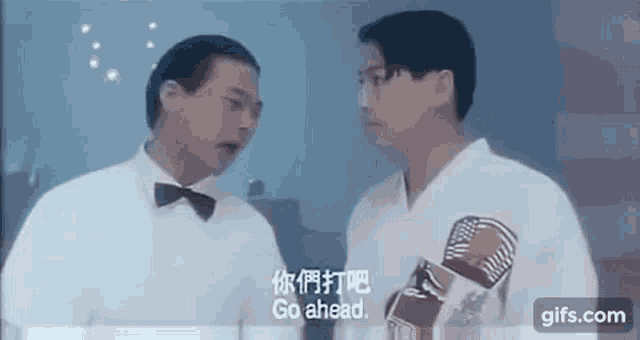 two men are standing next to each other in a room and talking to each other in chinese .
