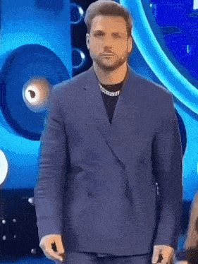 a man in a blue suit stands on a stage