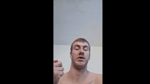 a man without a shirt is giving the middle finger to the camera .
