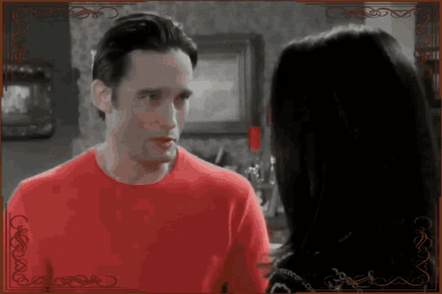 a man in a red shirt looks at a woman