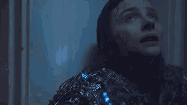 a close up of a person 's face with a blue light in the background