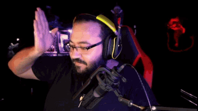 a man wearing headphones and glasses stands in front of a microphone with the letter e on it