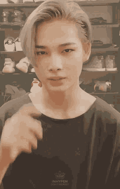 a young man with blonde hair is wearing a black shirt that says inhypen on it .