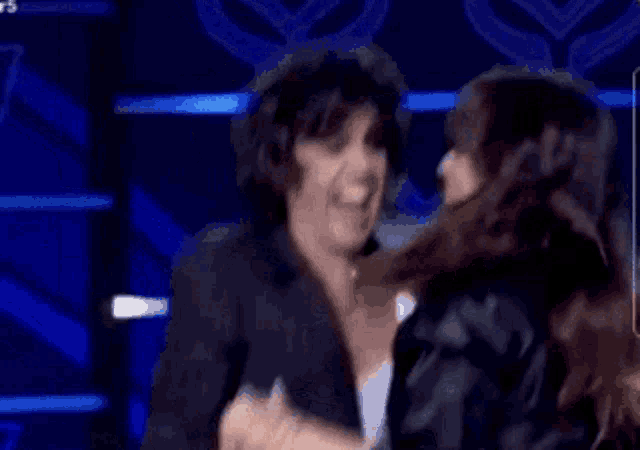 a man and a woman are giving each other a high five while sitting on a stage .