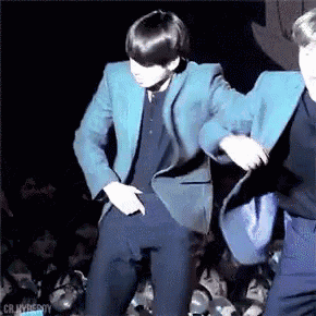 a man in a blue jacket is dancing on a stage