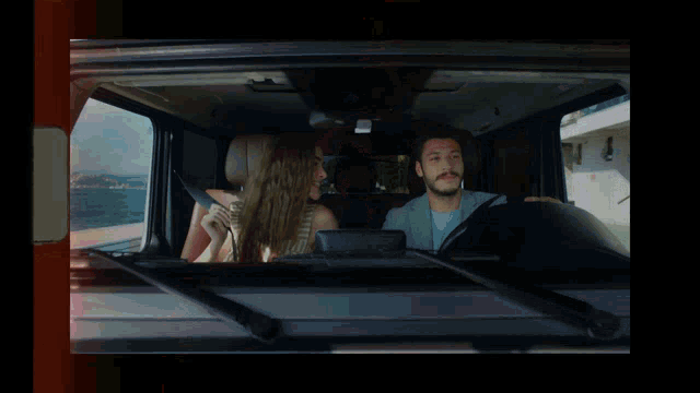 a man and a woman in a car looking out the window