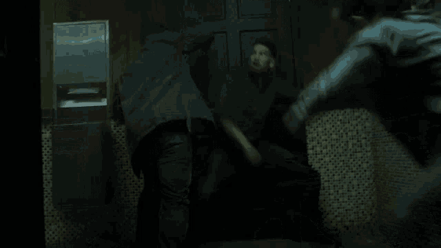 a group of people are fighting in a dark room with posters on the wall