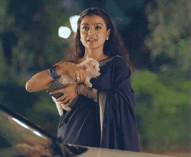 a woman in a black dress holds a small white dog in her arms