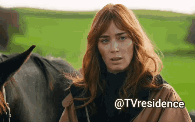 a woman with red hair is standing next to a black horse with the words @tvresidence written below her