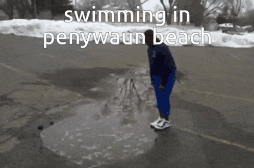 a person standing in a puddle with the words " swimming in penywaun beach " on the bottom