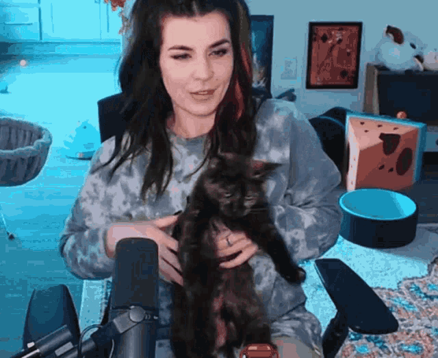 a woman holds a black cat in her arms in front of a microphone
