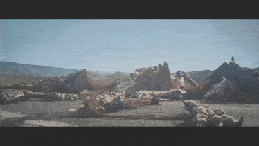 a large statue of a dinosaur is laying on the ground in a desert .