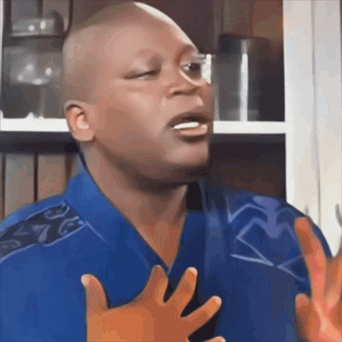 a man in a blue shirt is making a funny face with his hands in the air .