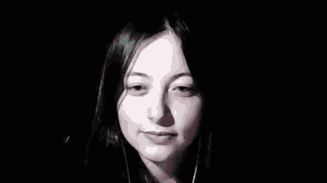 a close up of a woman 's face with headphones on in the dark .