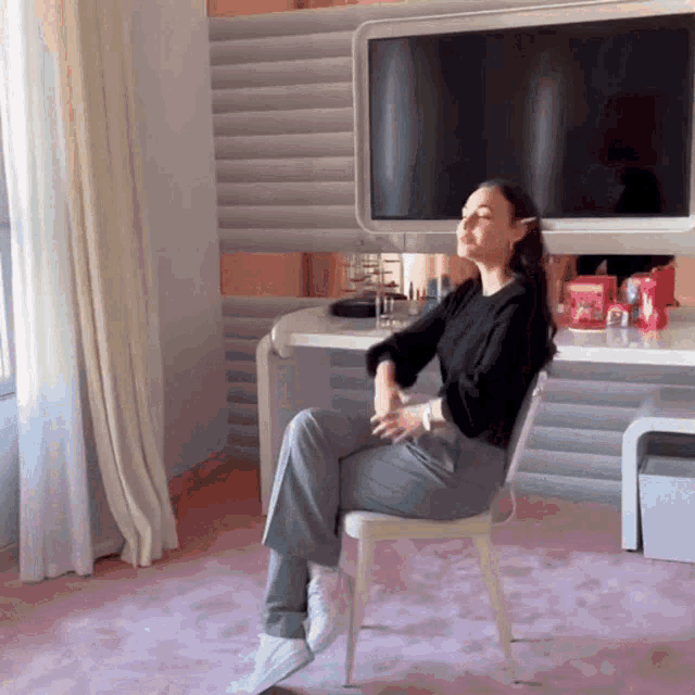 a woman is sitting in a chair in front of a television